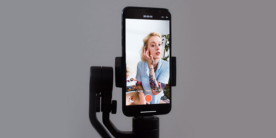 a smartphone on a gimbal and a female vlogger on its screen